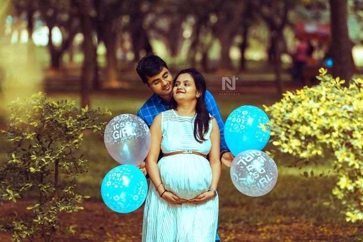 Couple holding balloons in a garden for a lighthearted and fun maternity photoshoot