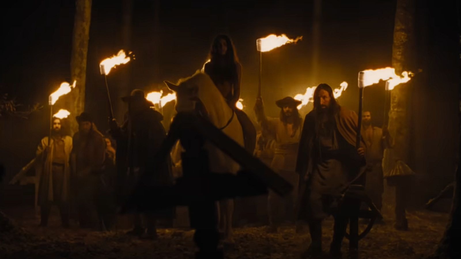 Group of people holding torches in a forest at night in Nosferatu