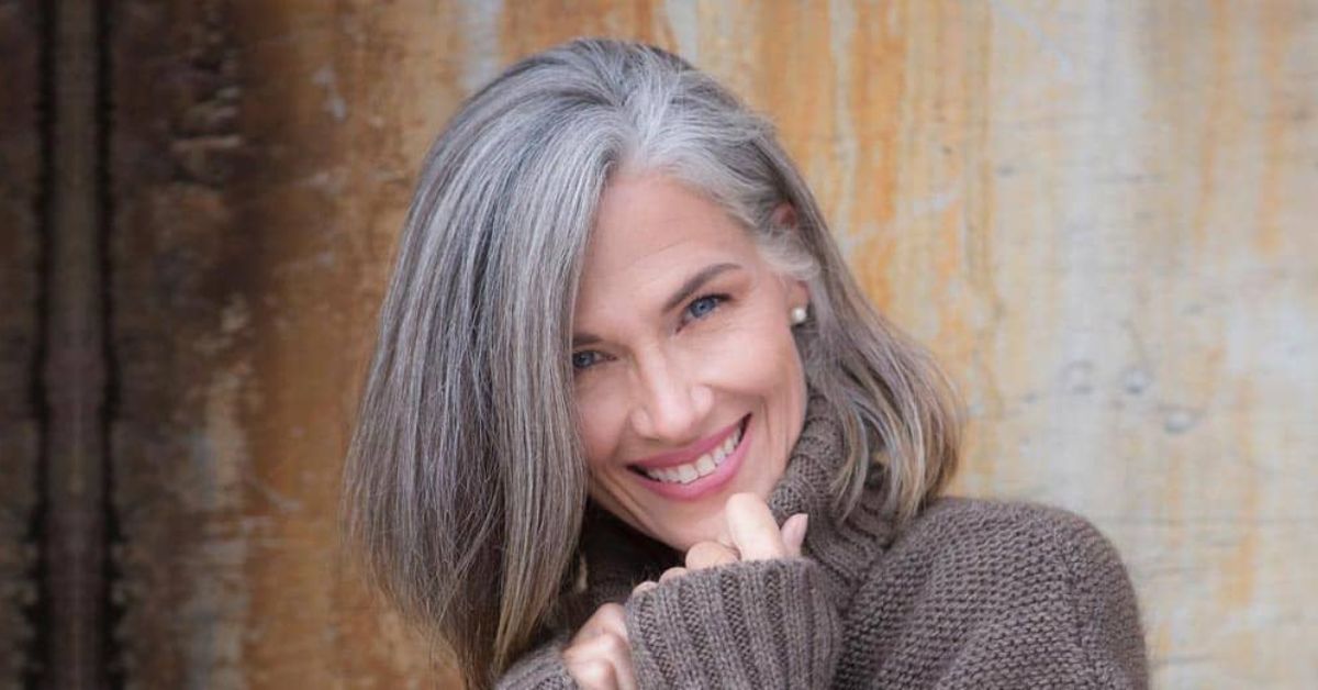 A woman with gray hair smiling, showcasing her elegant salt and pepper look with confidence and joy.