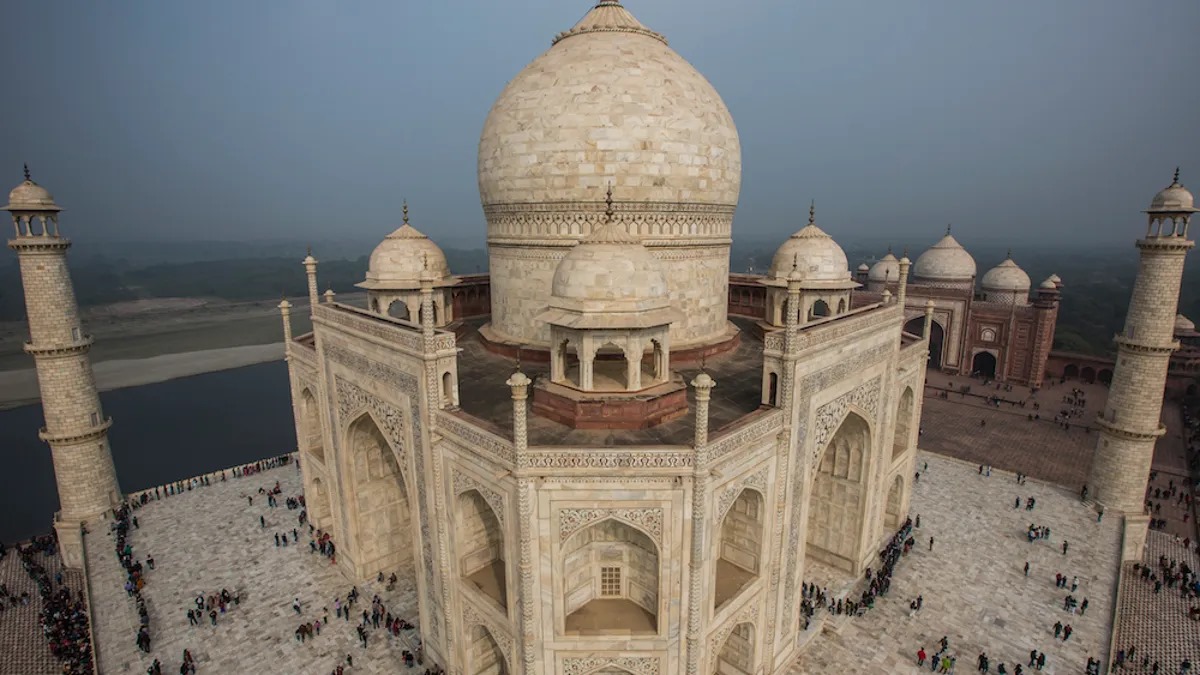 This aerial view showcases the white marble dome and four minarets of the Taj Mahal mausoleum.