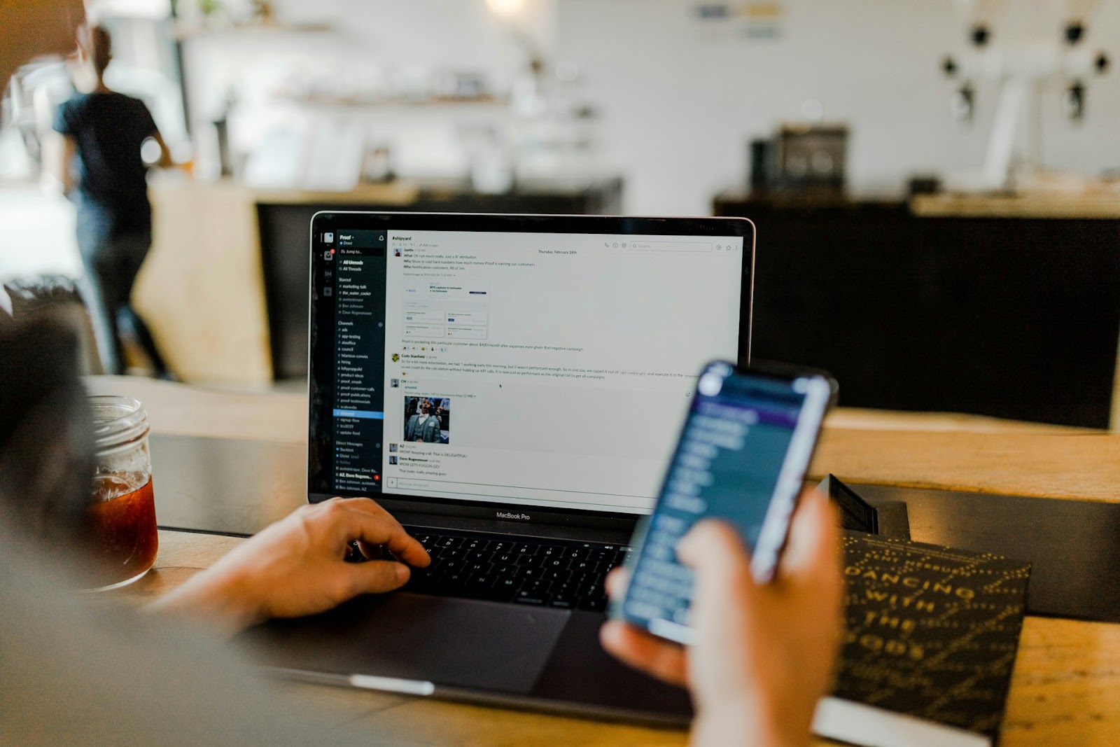 A person multitasking with a laptop open and a smartphone in hand, focused on their work or browsing online.