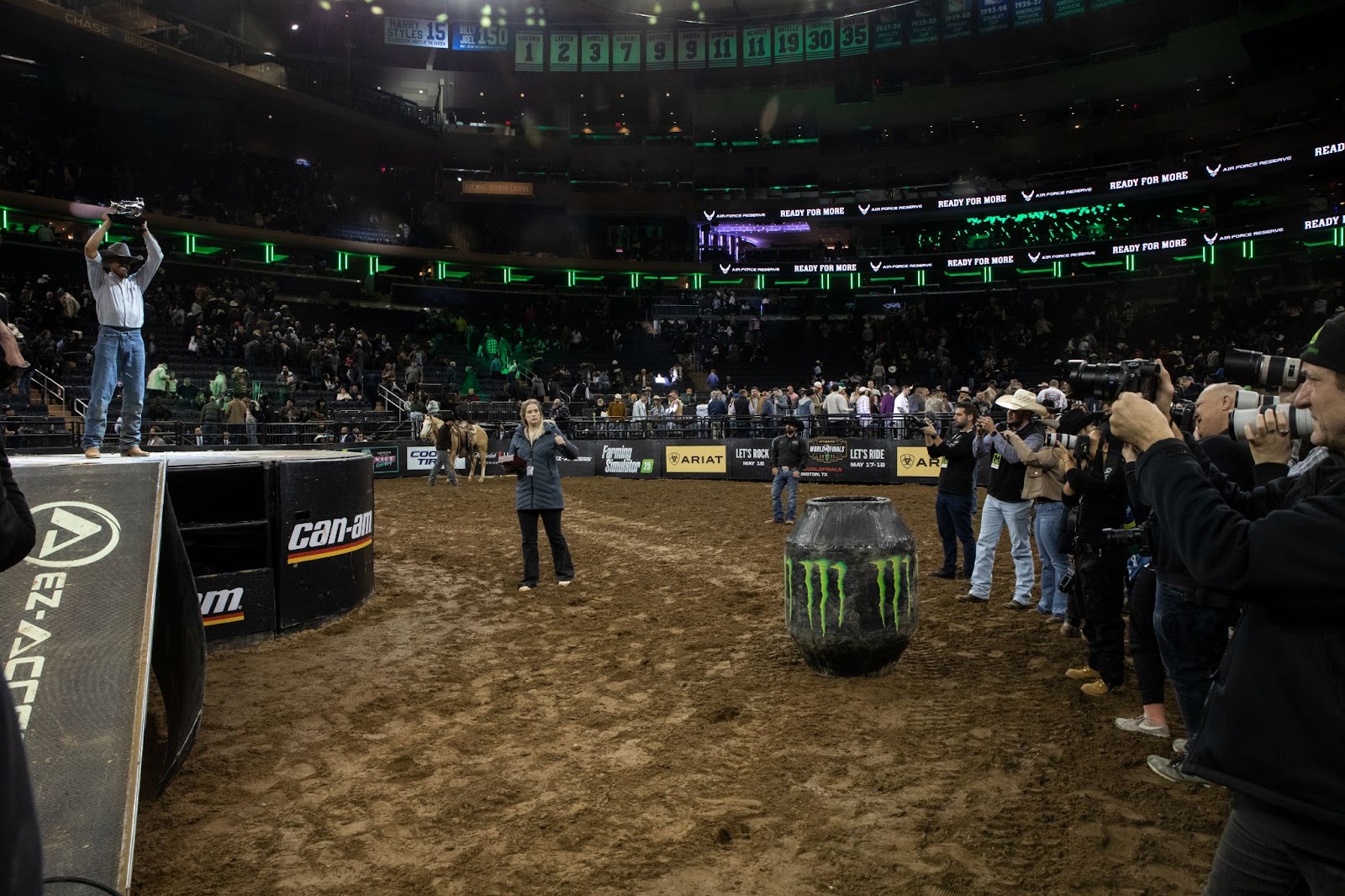 Winner Lucas Divino stands on pedestal and holds trophy above his head at the conclusion of the event. A line of press photographs him.