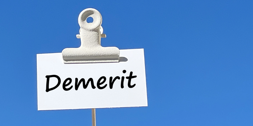 快晴の青空を背景に、木製クリップで留めた白いカードに黒文字で「Demerit」と書かれたシンプルなデメリット提示画像