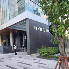 This contain: a man walking in front of a building with a sign that says hybe in