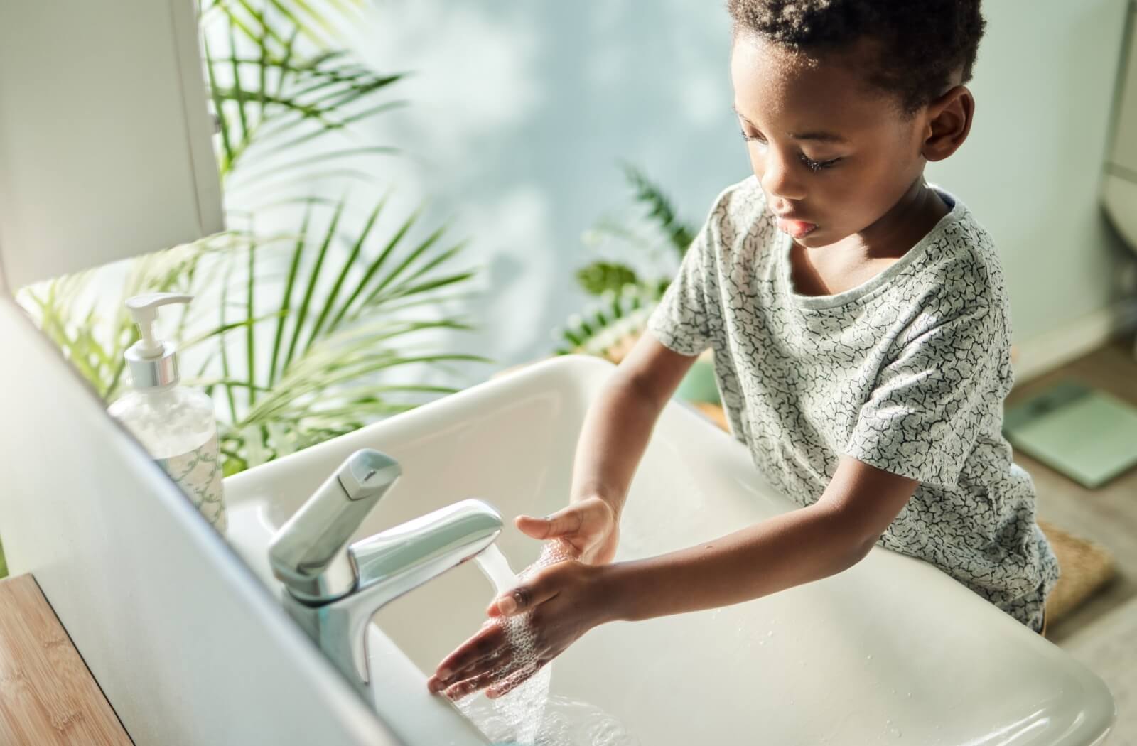 A child washing their hands in a brightly lit bathroom before they put their contact lenses in.