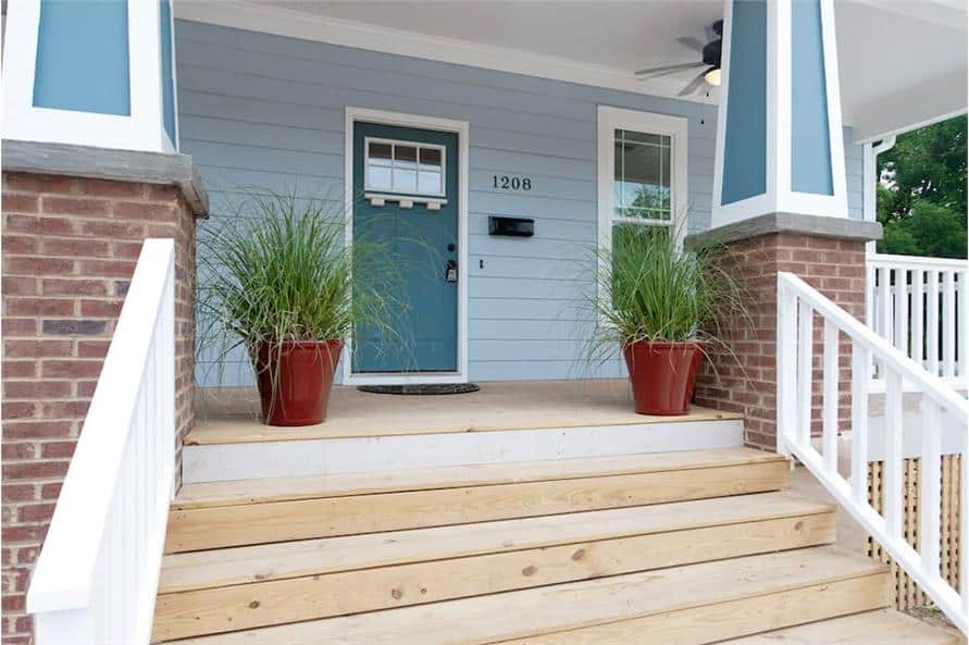 Covered front porch with a wooden stoop, tapered columns, and a blue entry door.