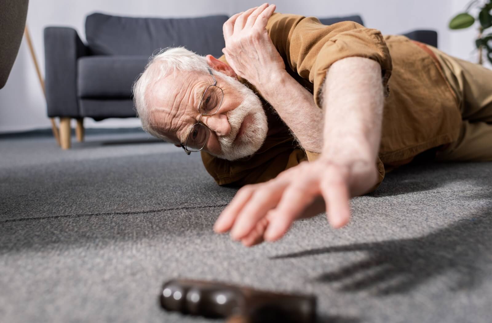 After falling on the ground, a senior reaches out for their out-of-reach cane in an attempt to get back to their feet