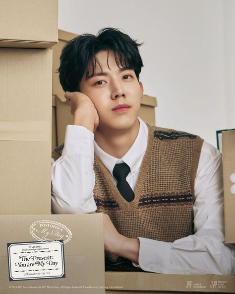 This contains an image of  DAY6 Dowoon sitting in front of boxes