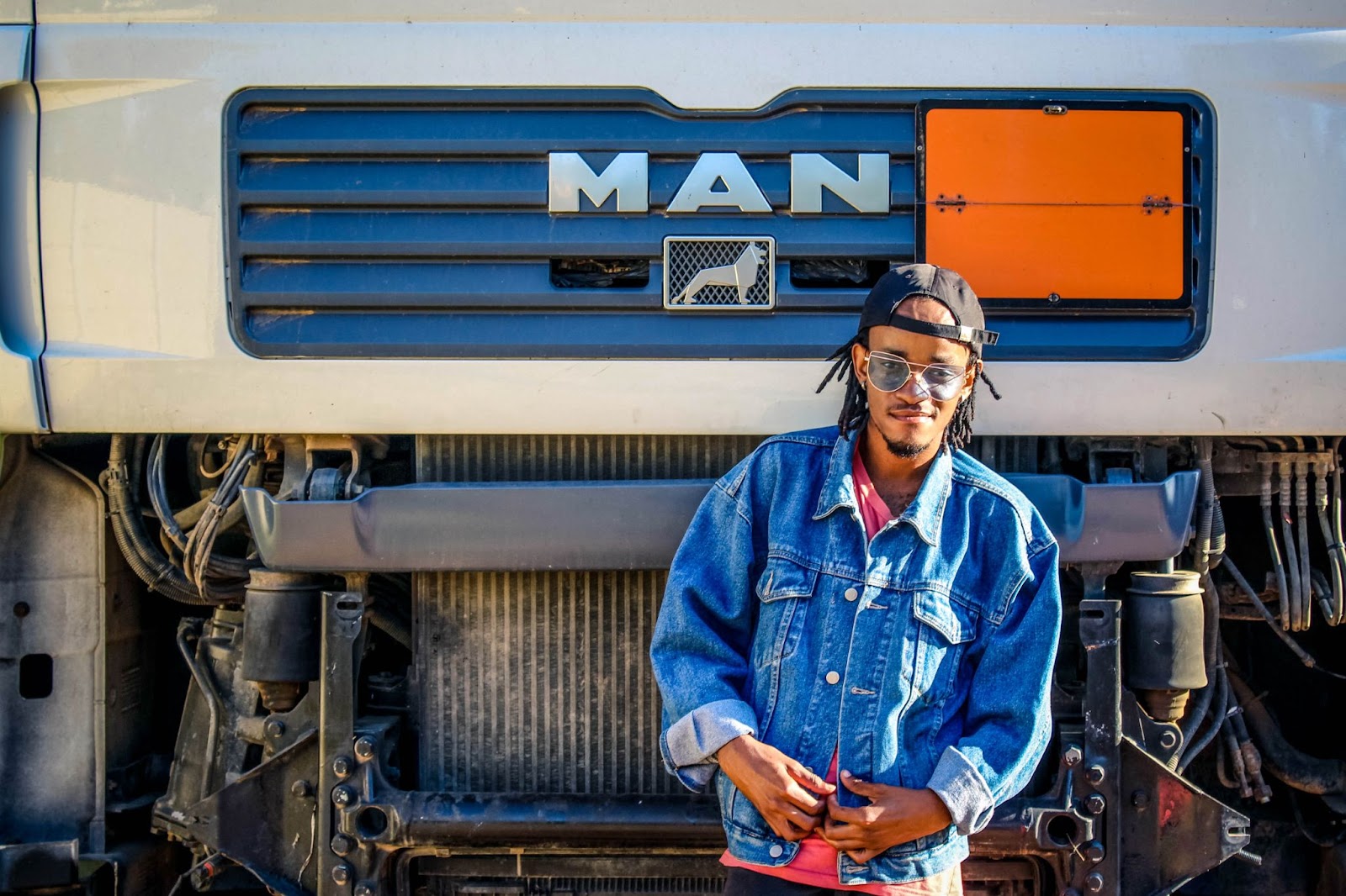 A person smiling in front of the hood of a MAN semi truck