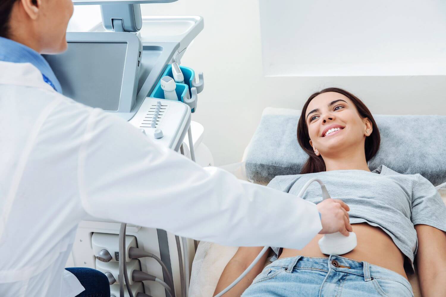 Woman in early pregnancy is on an exam table during an ultrasound at the doctor