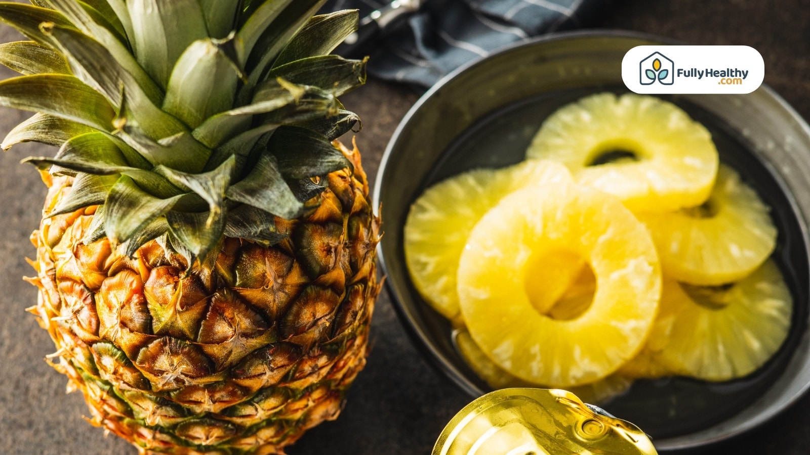 Whole pineapple and slices in bowl on table