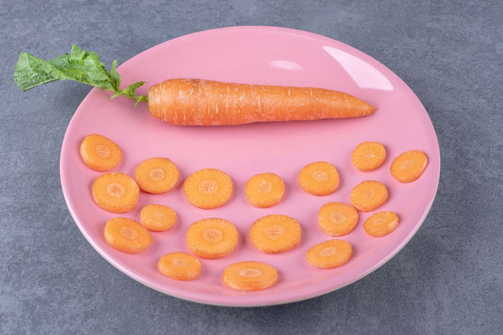 A whole carrot and sliced carrots on a plate