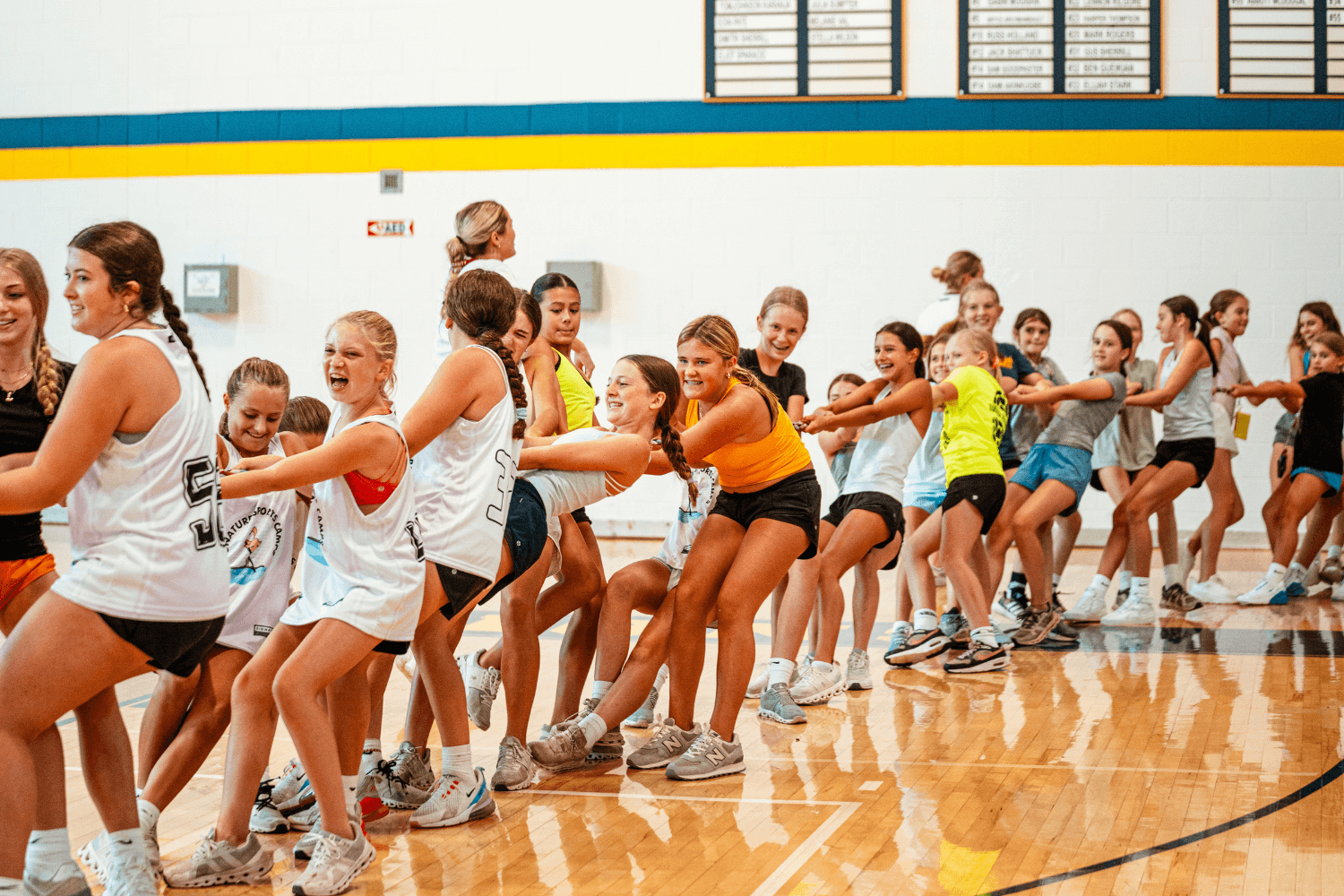 Group of girls at overnight sports camp actively engaged in a game of tug o war