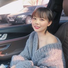 This  contain an image of Hong Young Gi sitting in the back seat of a car wearing a gray sweater and smiling