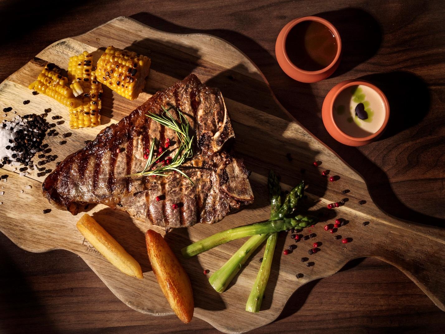 A steak and corn on a cutting board

Description automatically generated