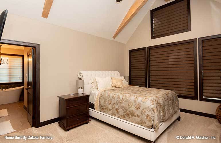 Primary bedroom with a vaulted ceiling, carpet flooring, and clerestory windows covered in brown blinds.