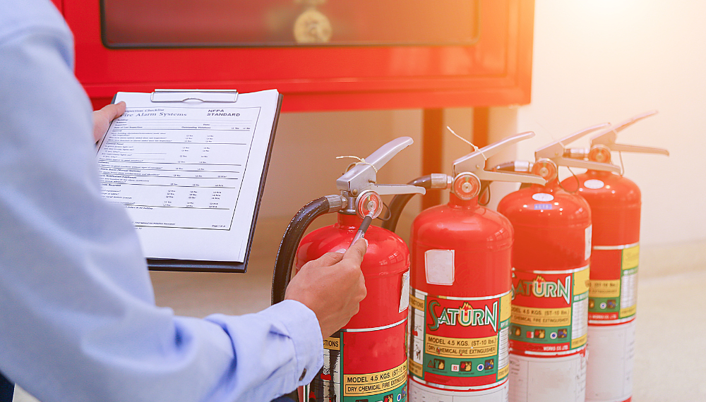 A person holding a clipboard and a fire extinguisher

Description automatically generated