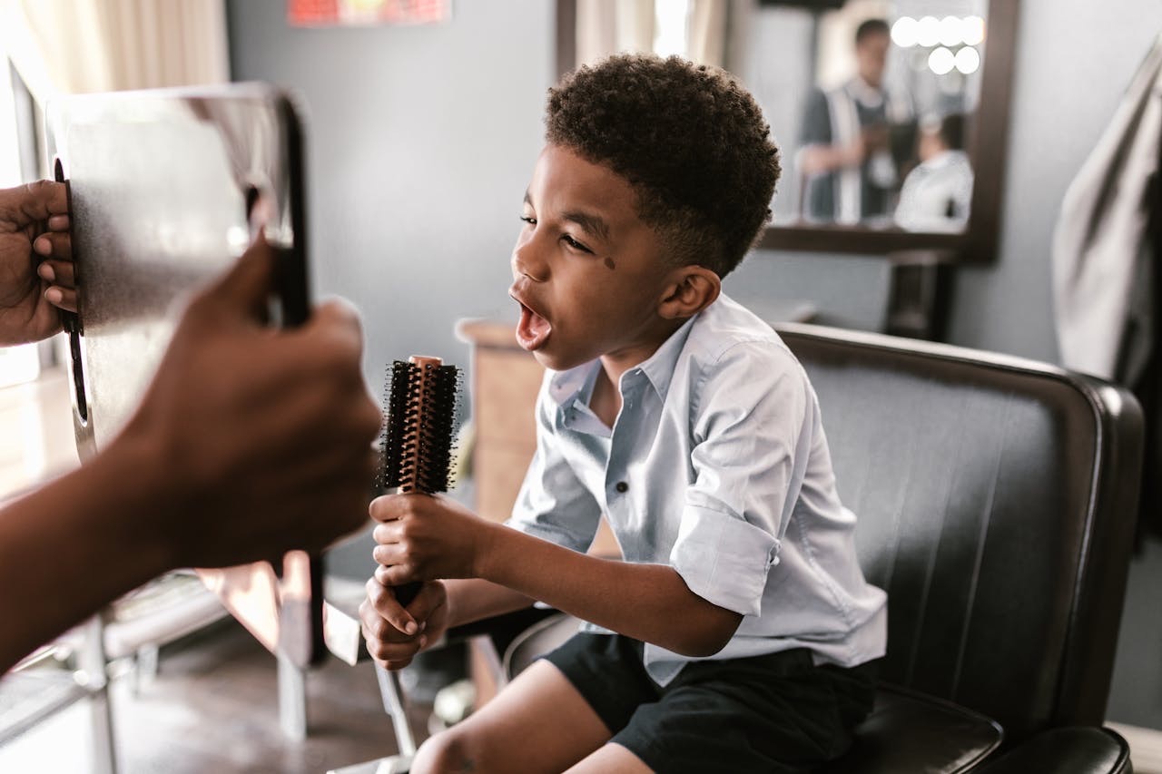 Boy singing in a barber shop with hair brush // Healthier Baby Today