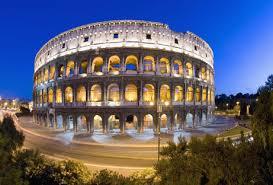 A circular building with many windows with Colosseum in the background  Description automatically generated