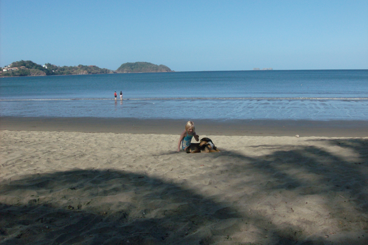 A girl playing with a dog at the beach of Playa Potrero.