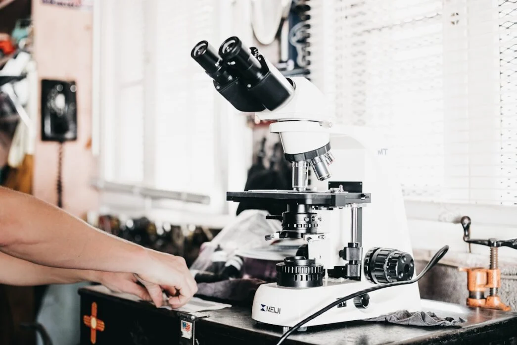 person-working-next-to-a-white-meiji-compound-microscope-on-a-laboratory-bench-livagen-for-aging-how-the-1-reverses-time-without-mainstream-approval-tony-huge