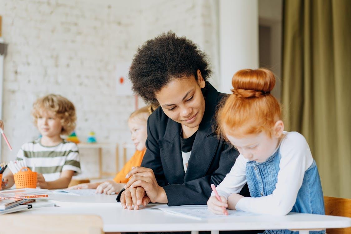 Free A Girl Writing On A Book Beside A Woman Stock Photo