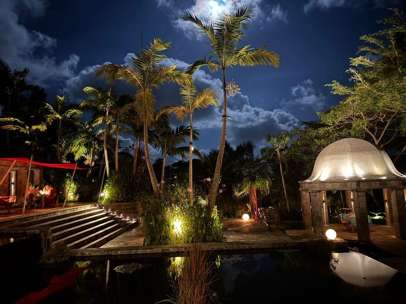 A pool with a gazebo and palm trees at night

AI-generated content may be incorrect.
