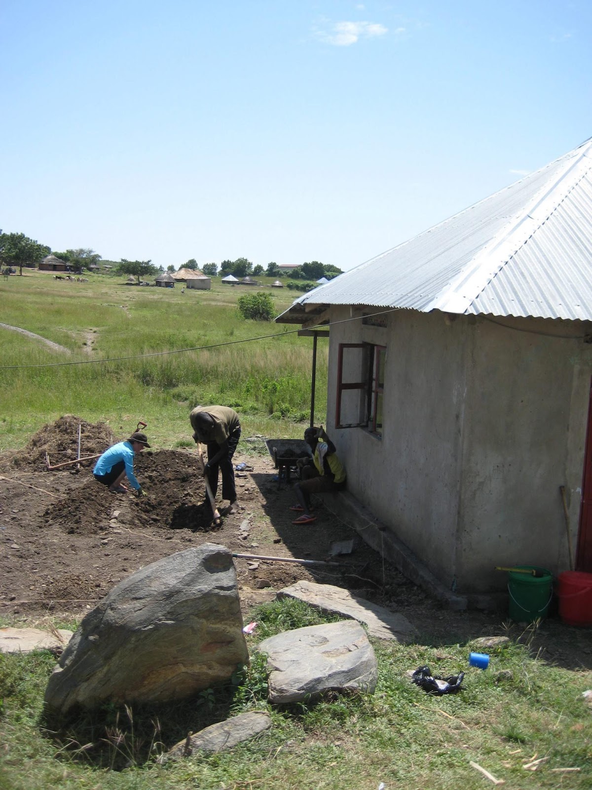 Woman and man digging next to a small concrete hut