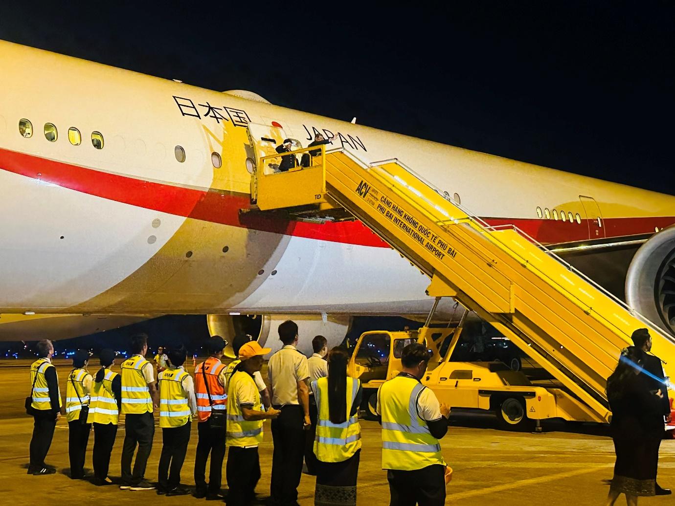 A group of people in yellow vests standing next to a planeDescription automatically generated