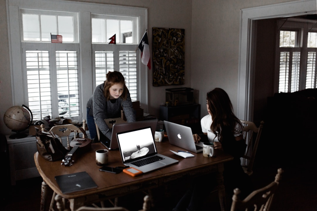 women using laptop on brown wooden table by Andrew Neel