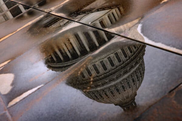 The dome of the U.S. Capitol, reflected in puddles on pavement.