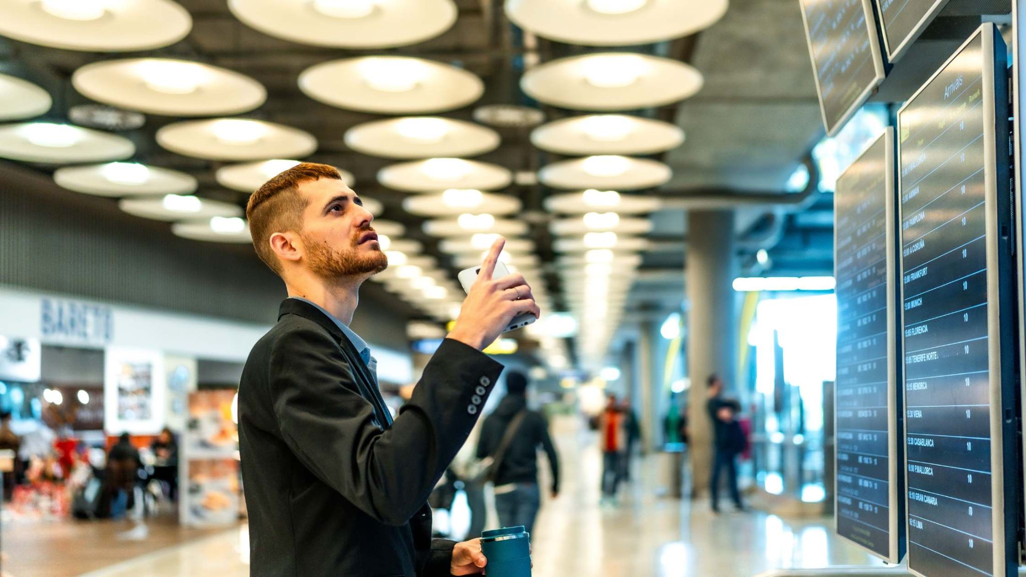 Seamless enterprise digital signage for airports and transit hubs in Qatar – DAC Qatar Business traveler checking flight information on digital signage displays at an airport, representing enterprise digital signage solutions in Qatar.