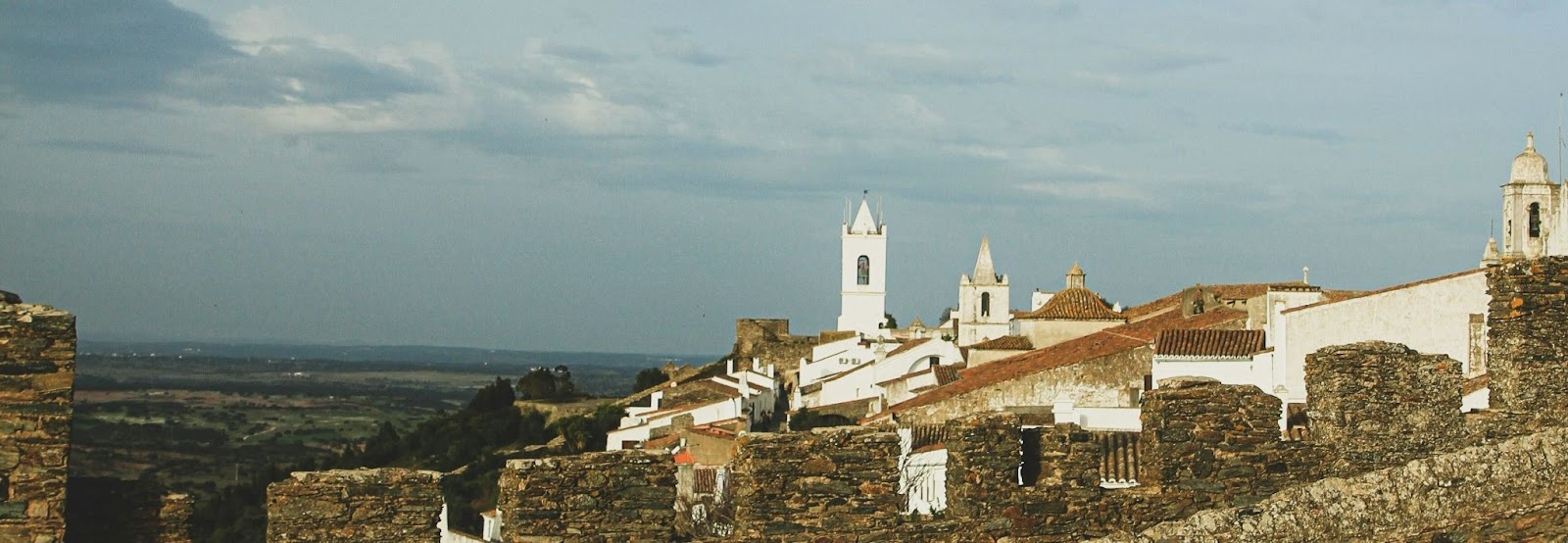 Vista panorâmica das construções históricas e muralhas de Monsaraz, vila medieval no Alentejo; descubra onde fica Monsaraz e seu charme único.
