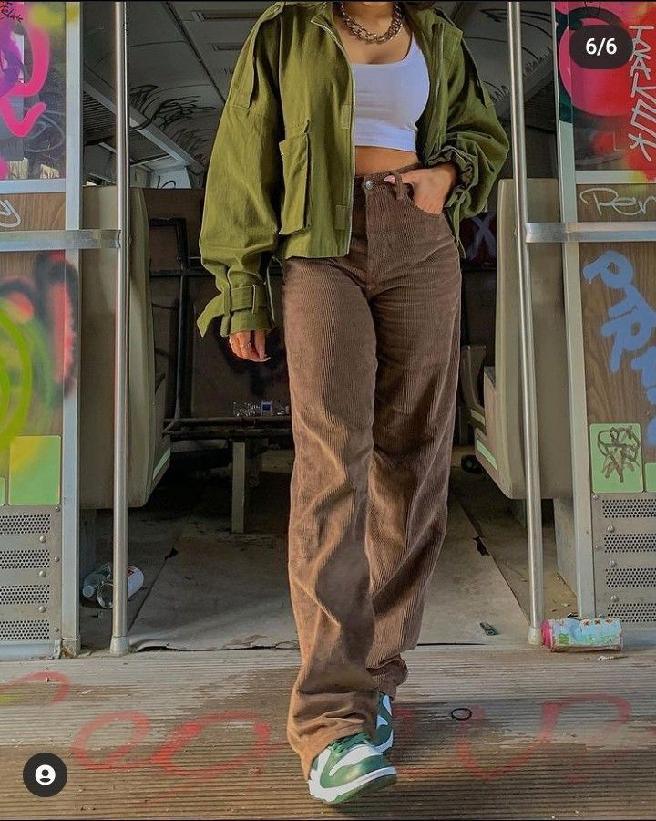 wanita memakai tank top putih, jaket hijau, celana cokelat, dan sneakers hijau putih