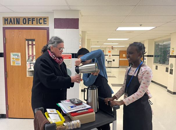 Dr. Reid being served tea by students at Poe Middle School. 