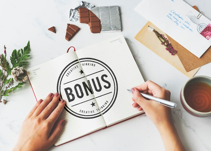 Shot of hands writing "bonus" on a notebook with other objects around