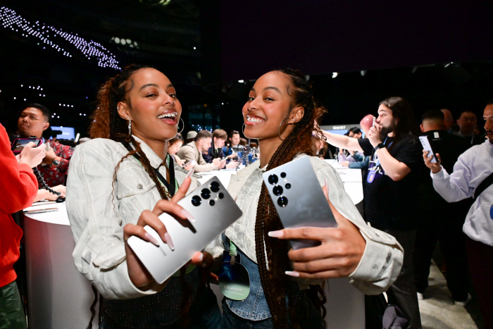 A couple of women holding cell phones

Description automatically generated