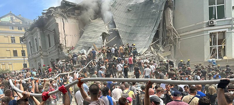 A group of people standing in front of a collapsed building

Description automatically generated