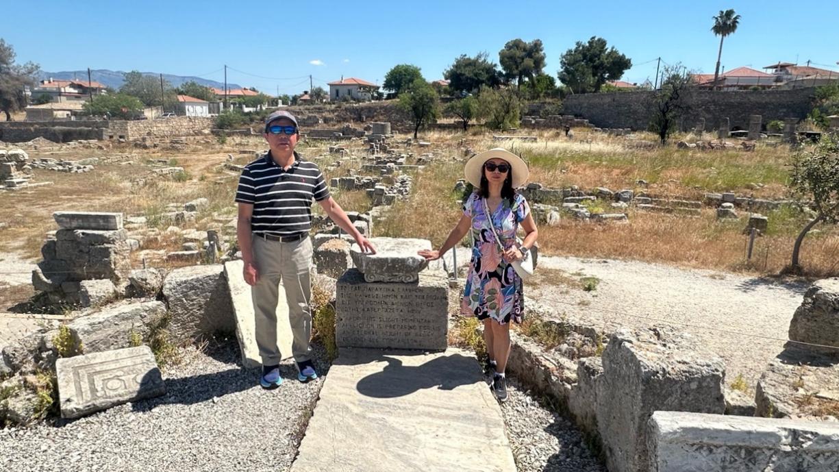 A person and person standing next to a stone monument

Description automatically generated