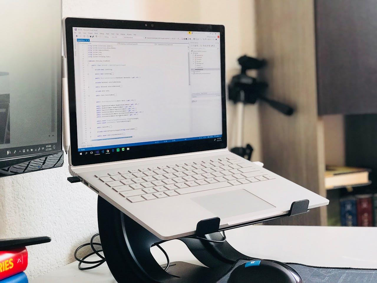 A white laptop placed on a laptop stand.