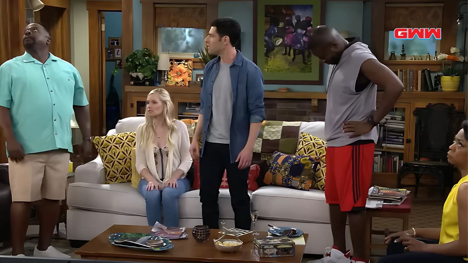 Cedric the Entertainer, Beth Behrs, Max Greenfield, and Sheaun McKinney in a living room discussion.