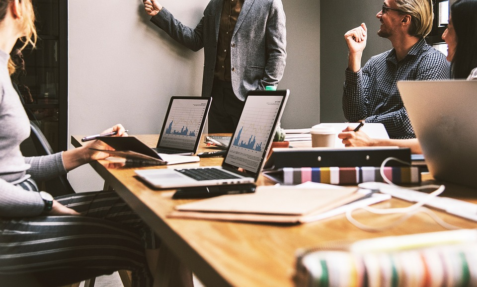 a group of business people wearing business casual working on laptop in an office meeting