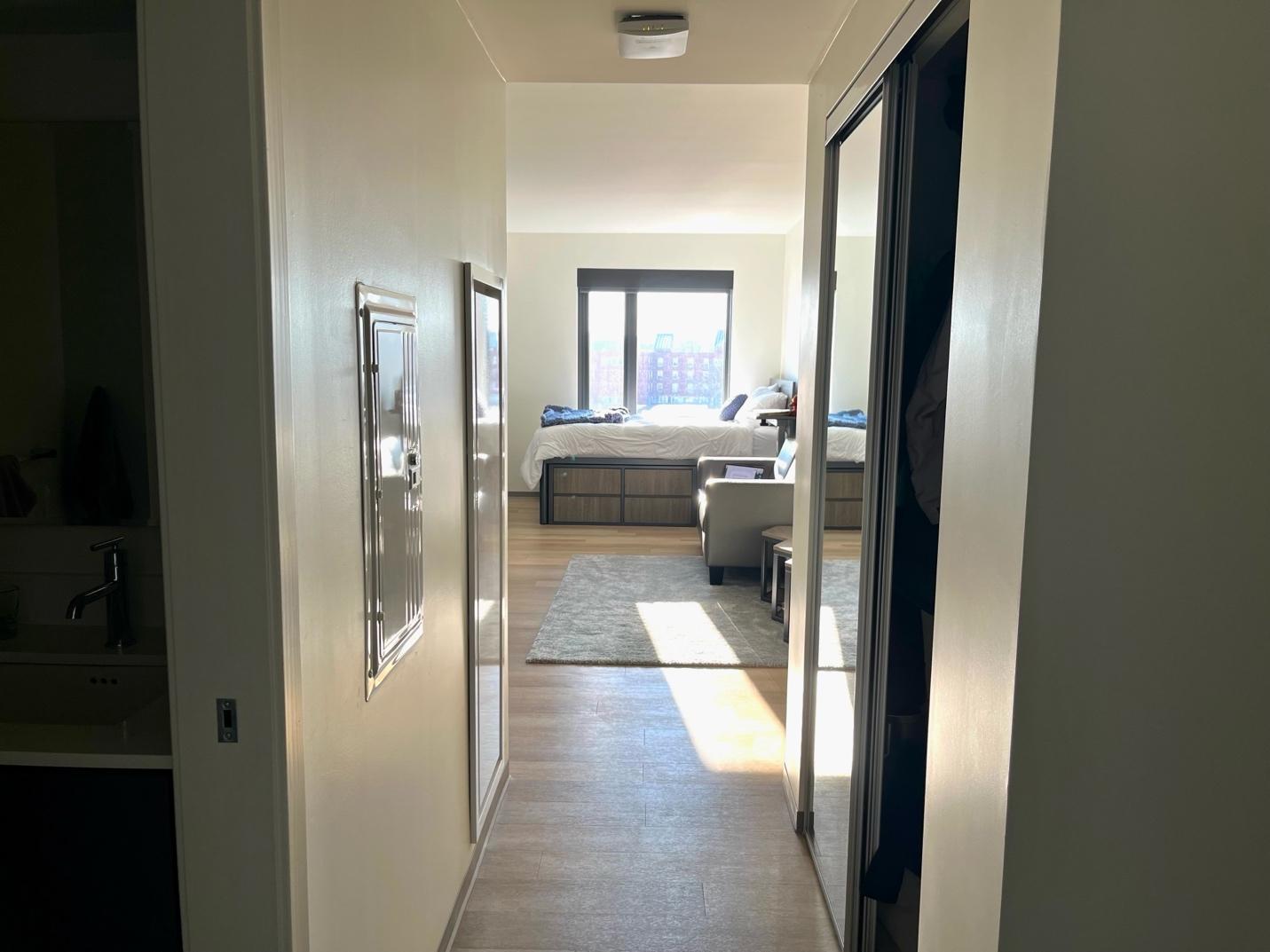 A hallway with a bed and a mirror

Description automatically generated