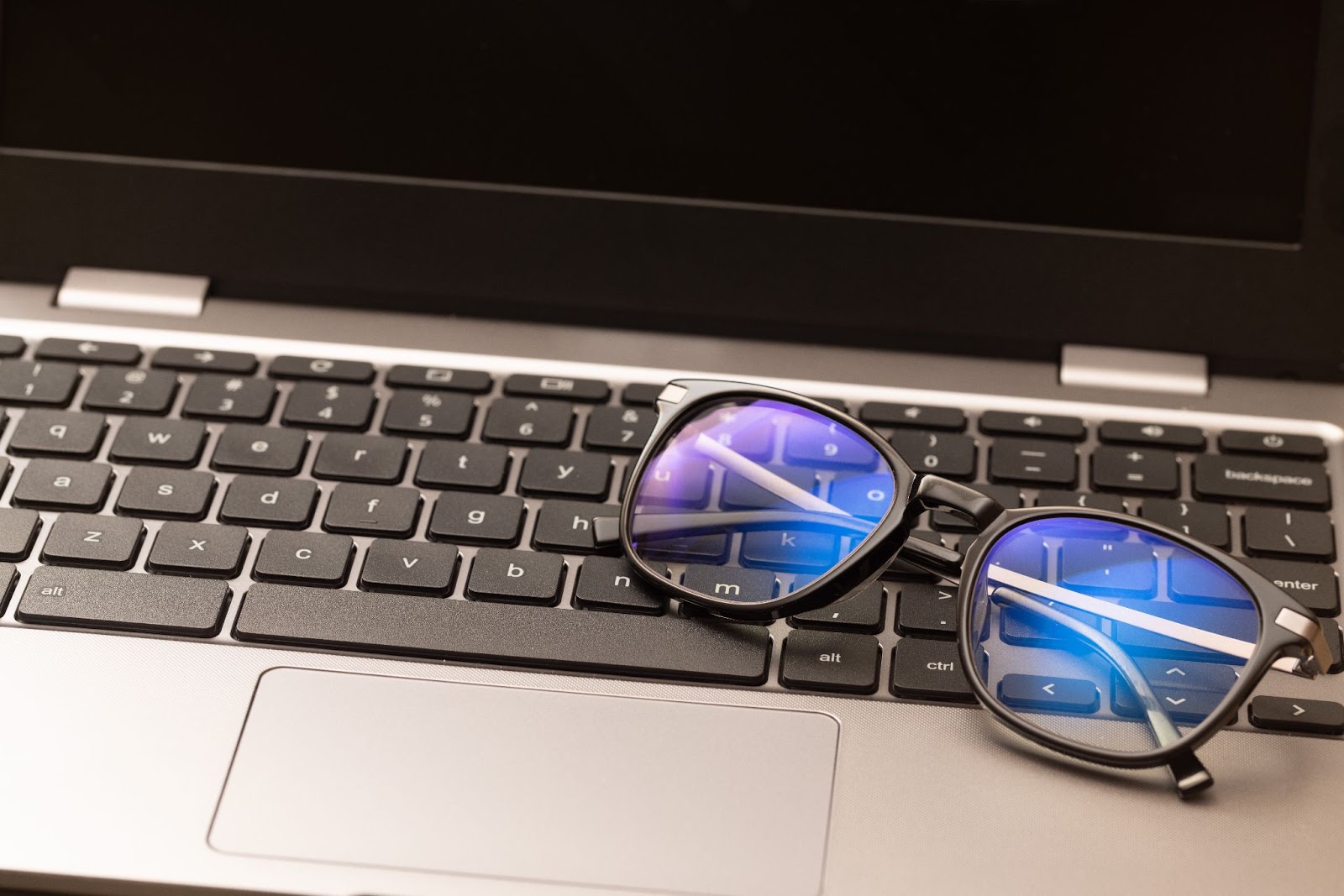 a pair of glasses are rested on a computer keyboard.