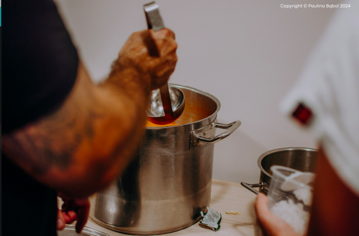 A person stirring soup in a pot

Description automatically generated