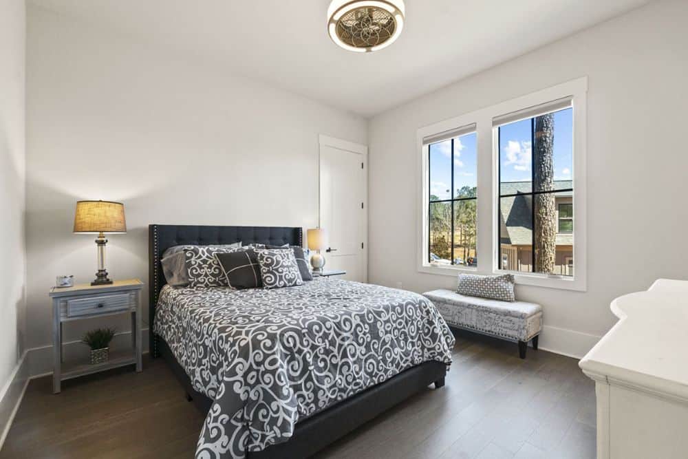 This bedroom offers a black tufted bed, light wood nightstands, and an upholstered bench.