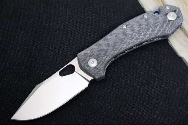 An image featuring the GiantMouse ACE Atelier folding knife, which has a clip-point blade and a black carbon-fiber handle.