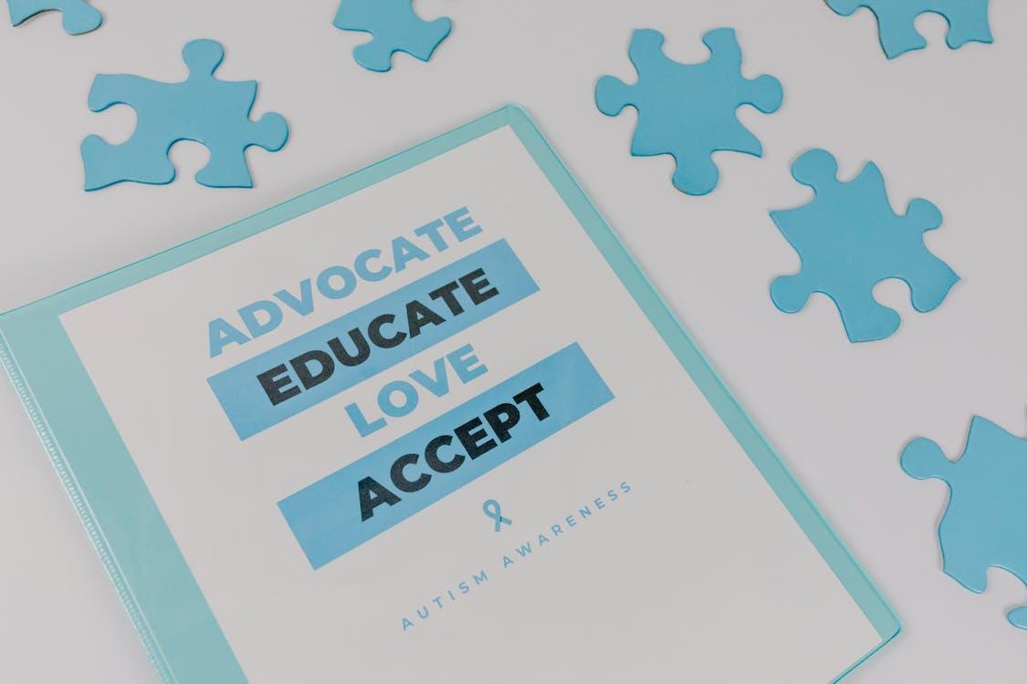 Free Binder with advocacy message amidst puzzle pieces for autism awareness. Stock Photo