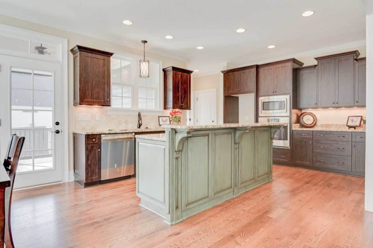 Kitchen with natural wood cabinetry, stainless steel appliances, granite countertops, and a two-tier island.