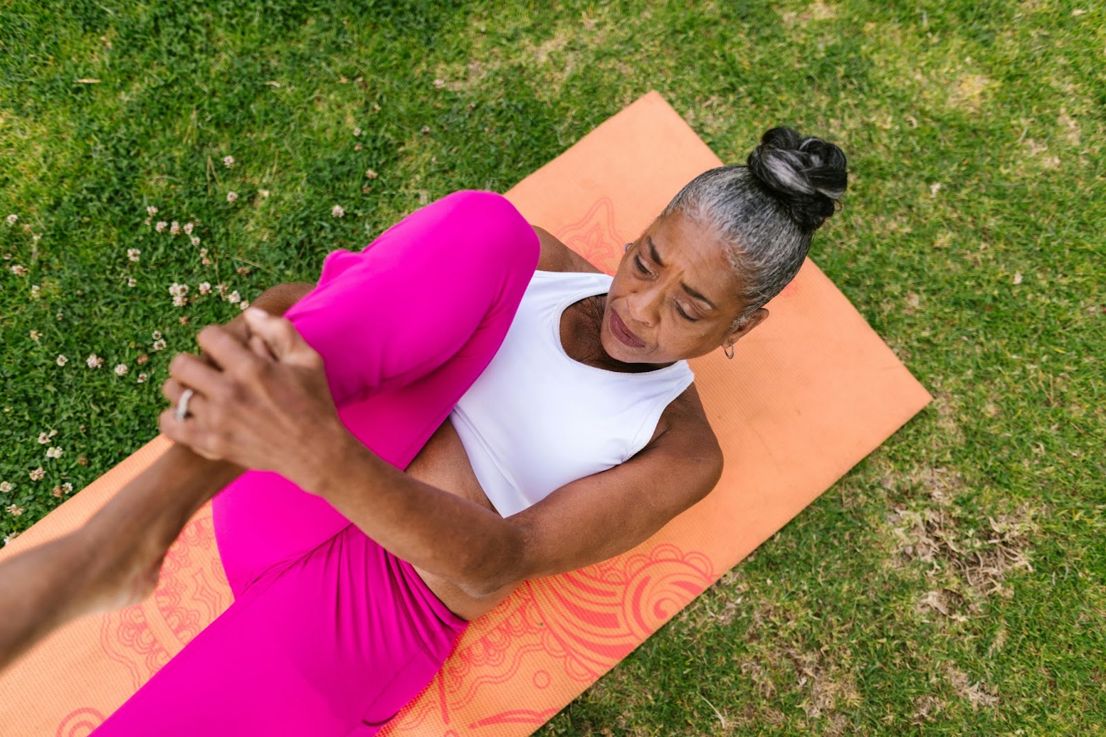 A senior doing a leg-strengthening exercise by hugging her ankles to her chest